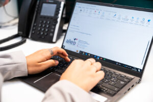 Mains d'une femme rédigeant un e-mail sur un ordinateur portable posé sur un bureau
